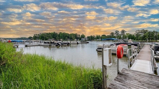 A marina with docked boats, a wooden pier, and a calm water body.
