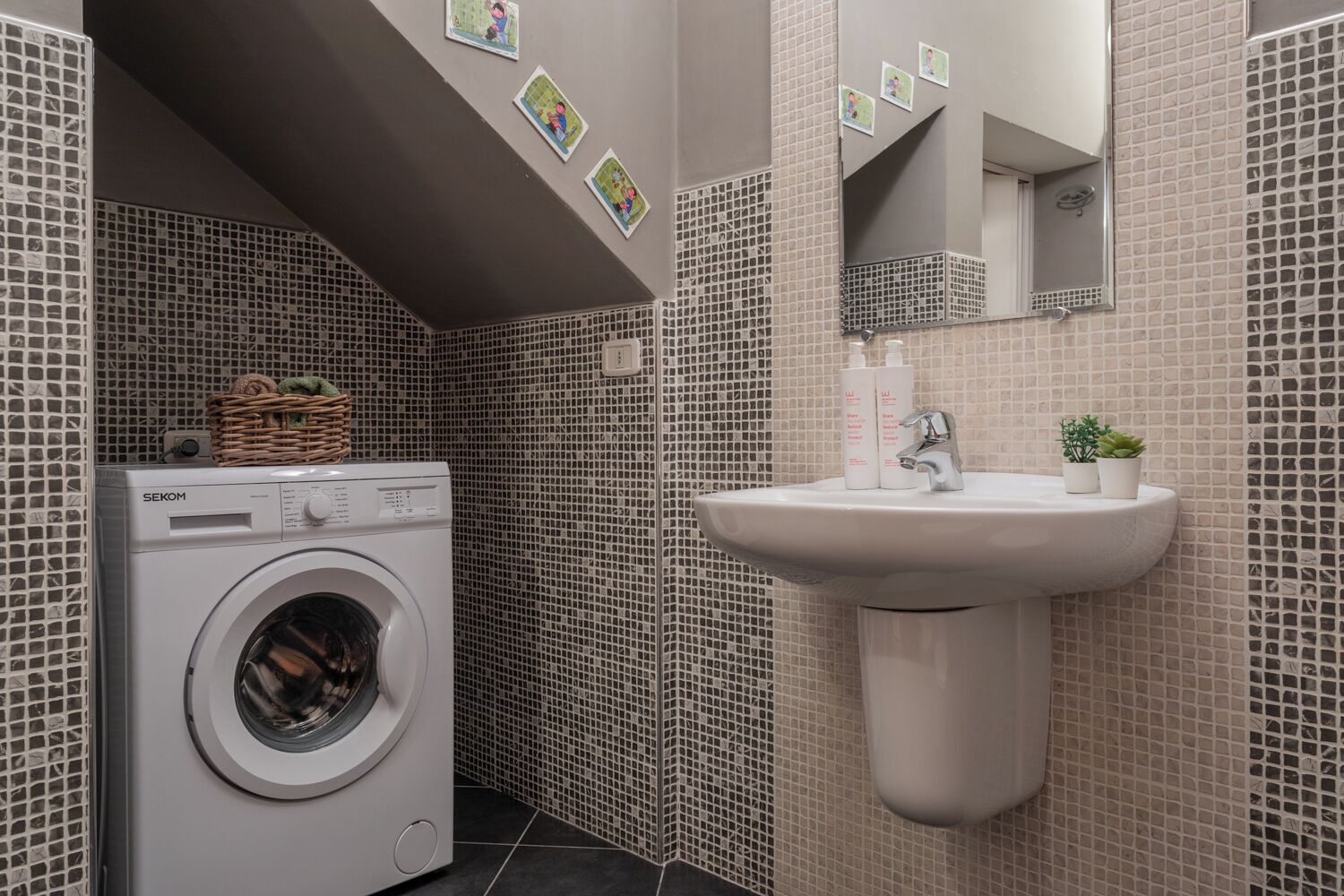 A compact bathroom with a washing machine, a sink, and tiled walls.