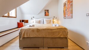 A bedroom with a large bed, a window, and a painting on the wall.
