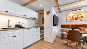 A modern kitchen with white cabinets, a wooden countertop, and a dining area with a glass table and chairs.