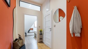 A hallway with a bench, a handbag, a mirror, and a door leading to a room.