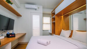 Une chambre d’hôtel avec un lit, une télévision, une étagère en bois et une fenêtre.