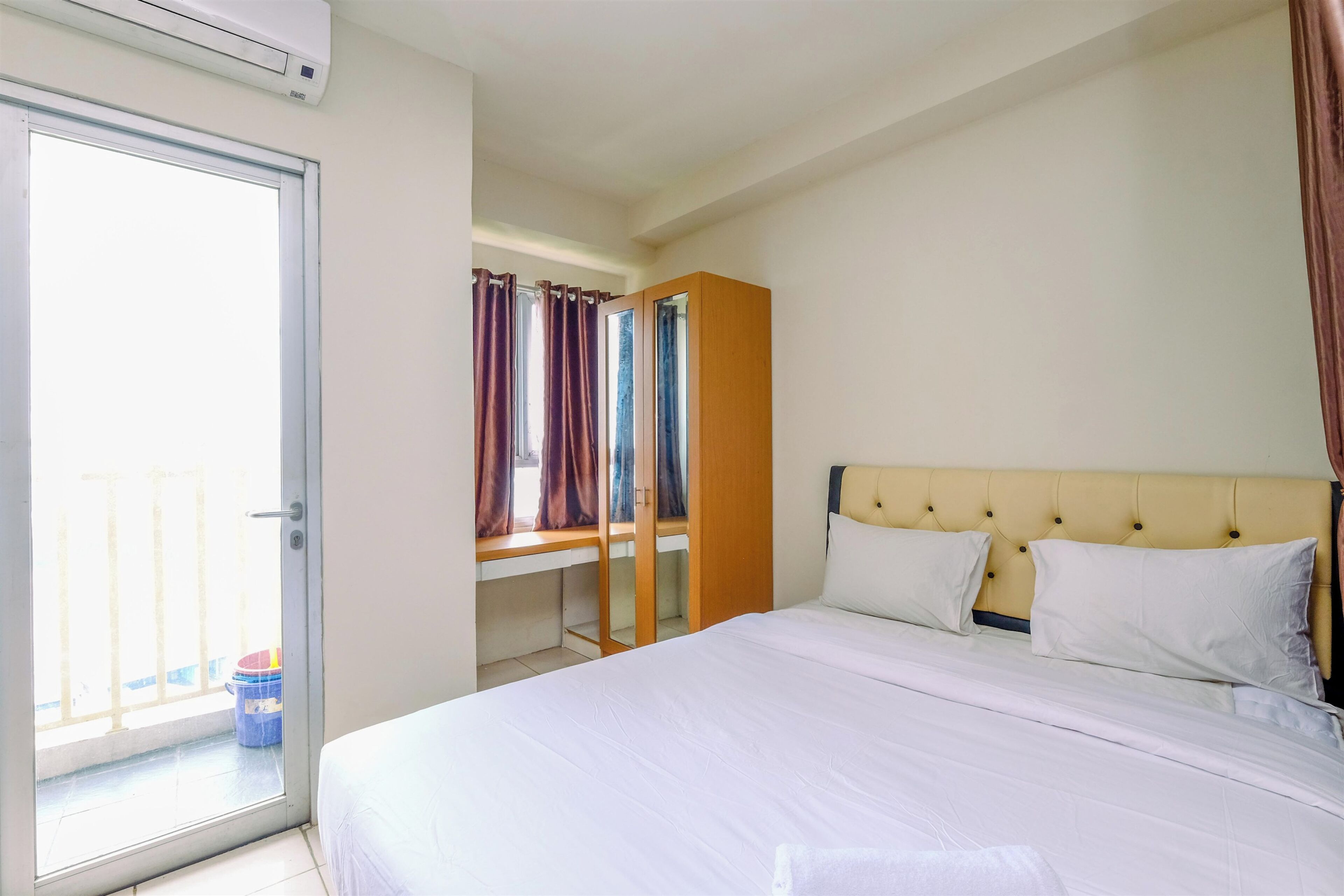A hotel room with a bed, a window with curtains, a desk, and a wardrobe.