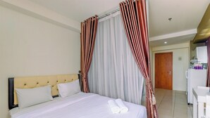 A hotel room with a bed, curtains, a desk, and a bathroom. - Comfortable And Tidy Studio At Titanium Square Apartment (Jakarta)