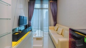 Ein modernes Wohnzimmer mit einer Couch, einem Couchtisch und einem Fernseher auf einem Glastisch.