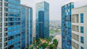 Ein Hochhaus mit einer markanten Glasfassade, umgeben von weiteren modernen Gebäuden.