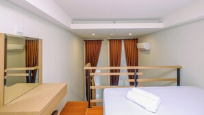 Une chambre d’hôtel avec un lit superposé, un bureau en bois, un miroir et une fenêtre avec des rideaux.