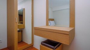 Une pièce avec une armoire en bois, un miroir et un petit banc.