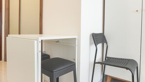 Ein Zimmer mit einem weißen Kleiderschrank, einem schwarzen Stuhl und einem weißen Tisch.