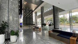 A spacious lobby with marble flooring, seating areas, and large windows offering views of the outdoors. - Good And Restful 1Br At The Smith Alam Sutera Apartment (Tangerang)