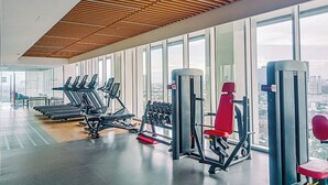 A gym with treadmills, dumbbells, and weight machines, large windows, and a wooden ceiling. - Good And Restful 1Br At The Smith Alam Sutera Apartment (Tangerang)