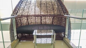 Un espace détente comprenant un banc rembourré et une petite table, le tout entouré d’une structure décorative en treillis.
