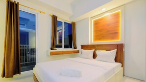 Une chambre d’hôtel avec un grand lit, une fenêtre avec des rideaux, une tête de lit en bois et un luminaire fixé au mur.