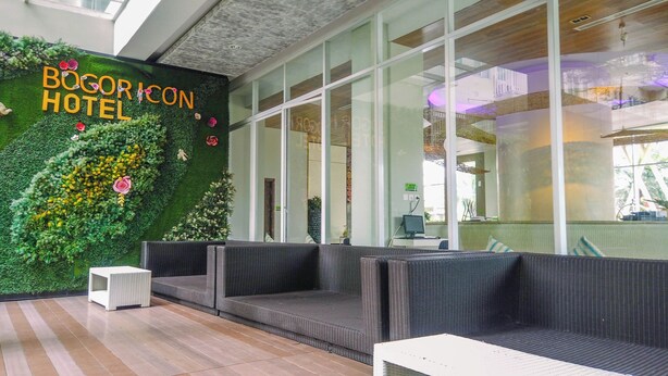Un hall d’hôtel moderne avec un mur végétal, un espace salon et de grandes fenêtres.