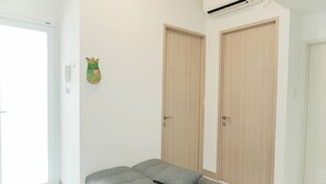 A room with a bed, two wooden doors, a wall-mounted phone, and an air conditioning unit. - Restful And Comfy 2Br Tokyo Riverside Pik 2 Apartment (Teluknaga)