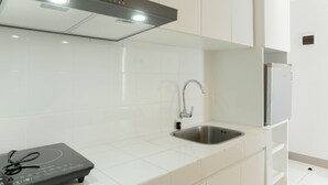 A modern kitchen with white tiles, a stainless steel sink, a Rinnai range hood, and a built-in refrigerator. - Restful And Comfy 2Br Tokyo Riverside Pik 2 Apartment (Teluknaga)