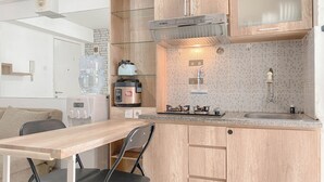 A compact kitchen with a wooden countertop, a built-in stove, a sink, and a large water dispenser.