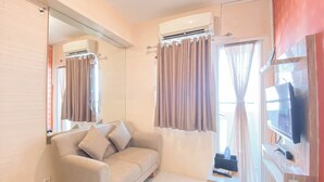 A modern room with a sofa, a TV, and an air conditioning unit.