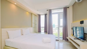 Een moderne hotelkamer met een groot bed, een flatscreen televisie en een balkon met gordijnen.
