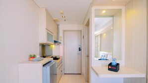 Een compacte hotelkamer met kitchenette, een kleine badkamer en zithoek.