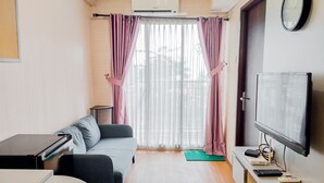 Un ambiente compatto con divano, un piccolo tavolo, una televisione e un condizionatore.