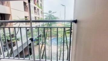 A balcony with metal railings overlooking a residential area with buildings and greenery.