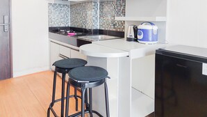 Una cucina compatta con lavello, due sgabelli, una macchina del caffè e un frigorifero.