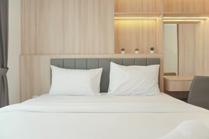 A hotel room with a bed, a bedside table, a mirror, and a small potted plant. - Cozy Living 2Br At Tokyo Riverside Pik 2 Apartment (Teluknaga)