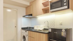 A compact kitchen with a washing machine, a microwave, and a refrigerator. - Cozy Living 2Br At Tokyo Riverside Pik 2 Apartment (Teluknaga)