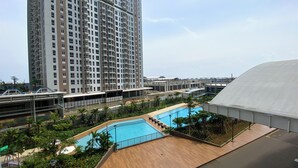 Un immeuble résidentiel moderne doté d’une piscine sur le toit et entouré de verdure.