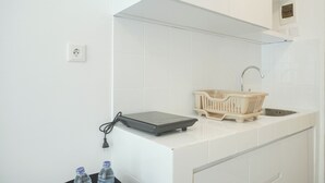 Une cuisine moderne avec des carreaux blancs, un évier encastré, un plan de travail muni d’une balance et une petite plante accrochée au mur.