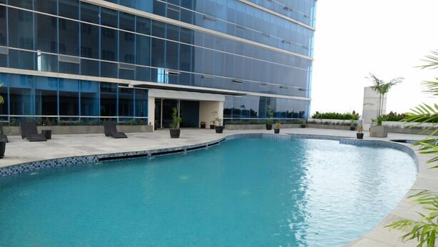 A modern building with a swimming pool, lounge chairs, and potted plants. - Simple And Comfortable Living 1Br At The City Square Apartment (Surabaya)