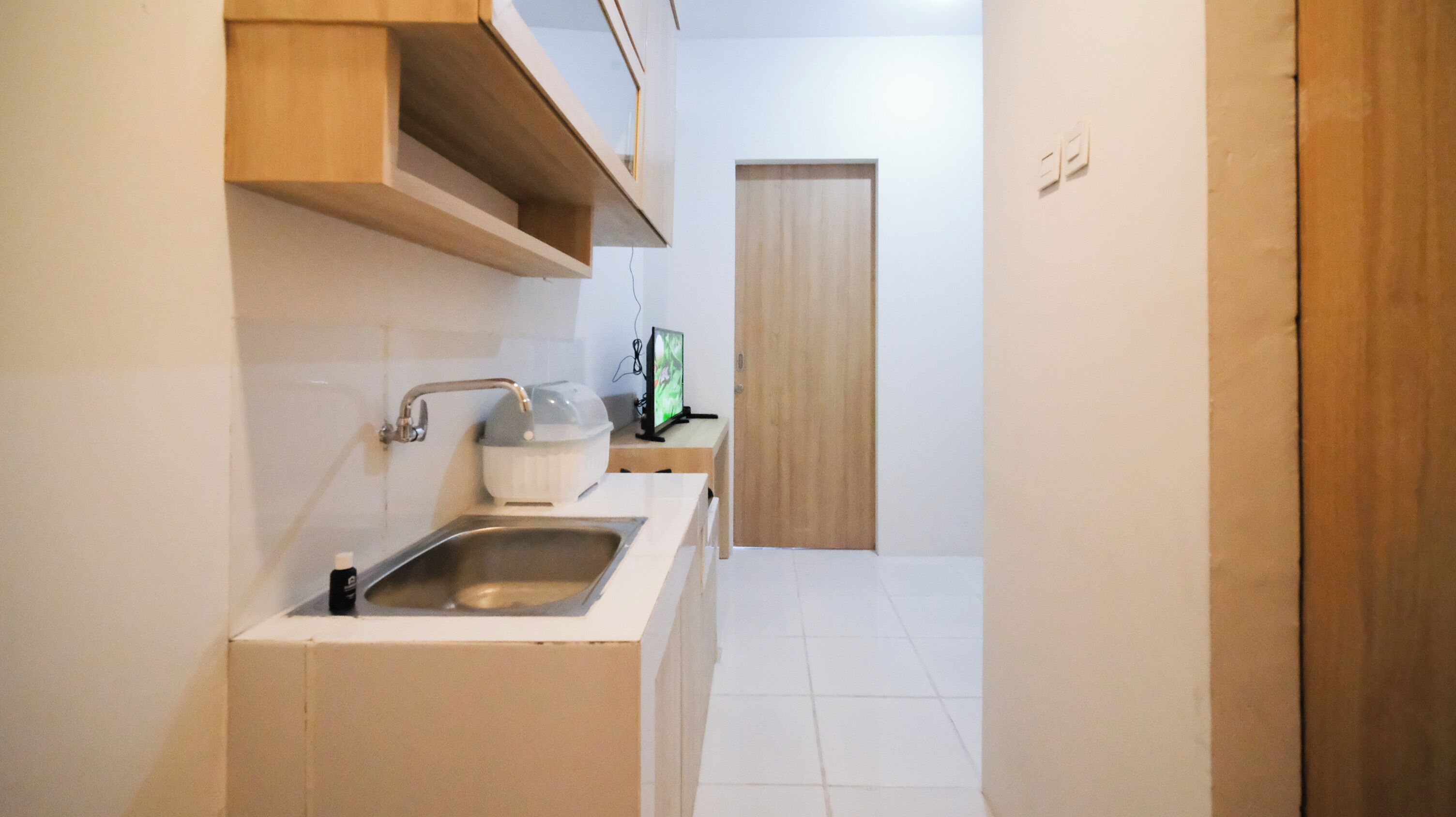 Una pequeña cocina con un lavabo, una encimera y un armario de madera.