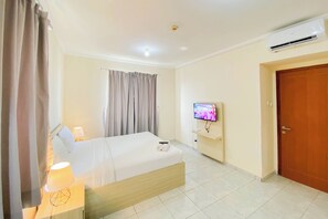 Una camera d'albergo con un letto, una televisione, un condizionatore d'aria e una porta.