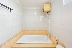 Un bagno con una vasca, un water e uno scaldabagno a parete.