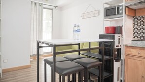 Una cucina compatta con un piano di lavoro bianco, un forno a microonde, un erogatore d'acqua e un piccolo forno.
