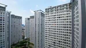 Un edificio residenziale a grattacielo con facciata a griglia, numerosi balconi e un cortile centrale con vegetazione.
