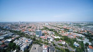A cityscape with a mix of residential and commercial buildings, including high-rise structures and smaller houses. - Best Location And Restful 1Br At The City Square Apartment (Surabaya)