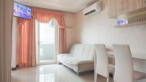 Un salon moderne comprenant un canapé, deux fauteuils, un téléviseur à écran plat et un appareil de climatisation.