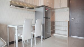 Une cuisine moderne dotée d’un réfrigérateur encastré, de chaises blanches et d’armoires en bois.