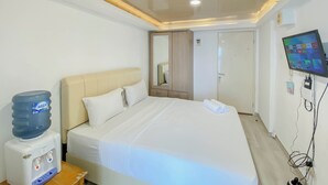 Ein Hotelzimmer mit Bett, Wasserspender, Fernseher und Kleiderschrank.