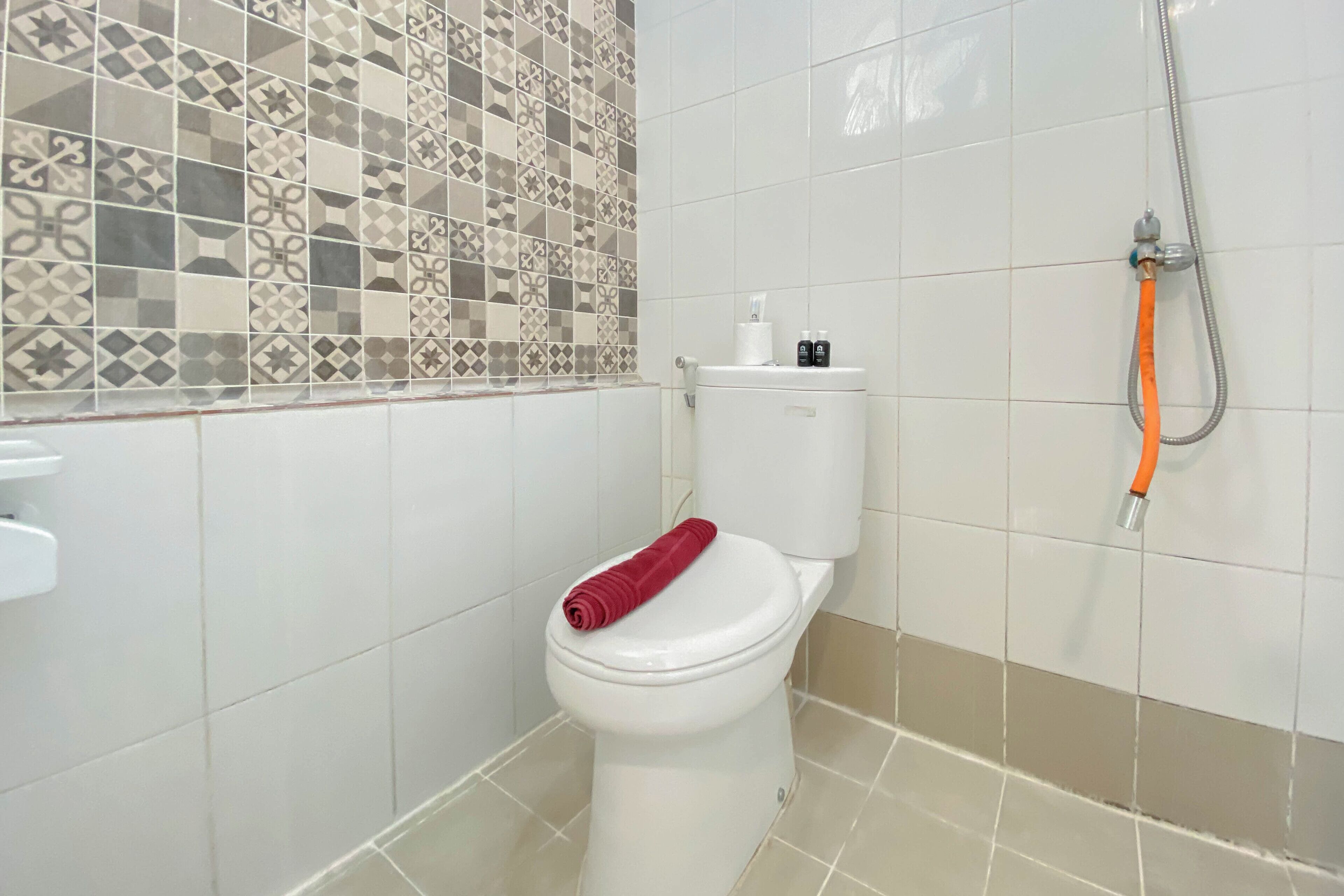 Ein Badezimmer mit Toilette, Dusche und Fliesen.