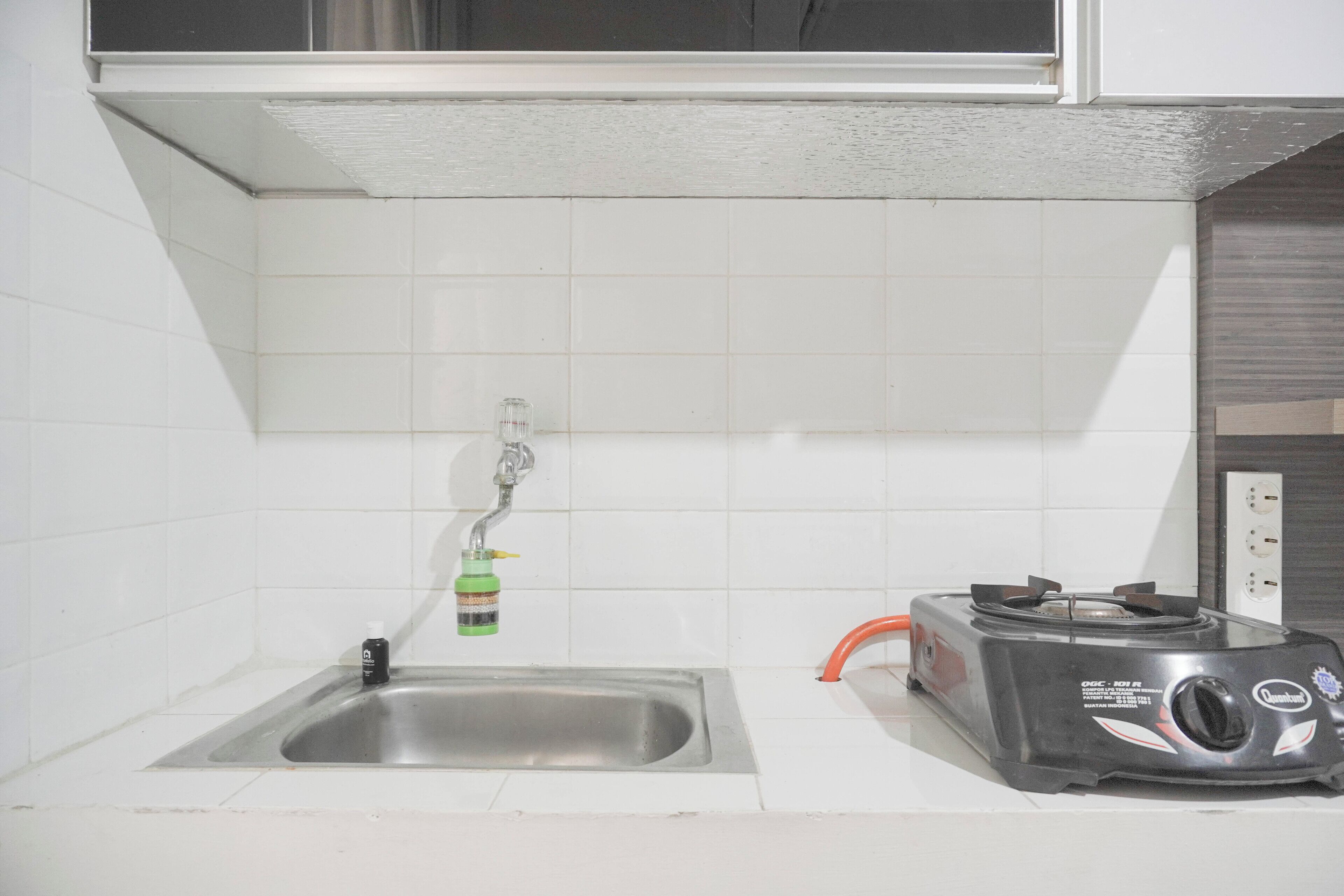 A kitchen with a stainless steel sink, a gas stove, and a window above the sink.