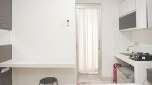 A compact kitchen with white cabinets, a built-in microwave, and a gas stove. - Cozy Living Studio At Green Bay Pluit Apartment (Jakarta)