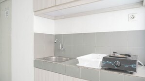 A kitchen with a double sink, a Rinnai electric kettle, and a white countertop.