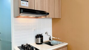 A compact kitchen with a gas stove, a built-in oven, and a sink. - Comfort Designed 2Br Green Pramuka City Apartment (Jakarta)