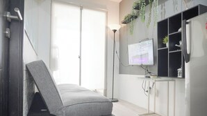 Una habitación moderna con una cama, un escritorio, un ordenador y un refrigerador.