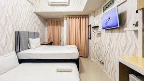 A hotel room with a bed, a desk, a television, and a wall-mounted air conditioner. - Good Place Studio Apartment At Vida View Makassar (Makassar)