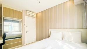 Une chambre d’hôtel avec un lit, un bureau, une armoire et une fenêtre.