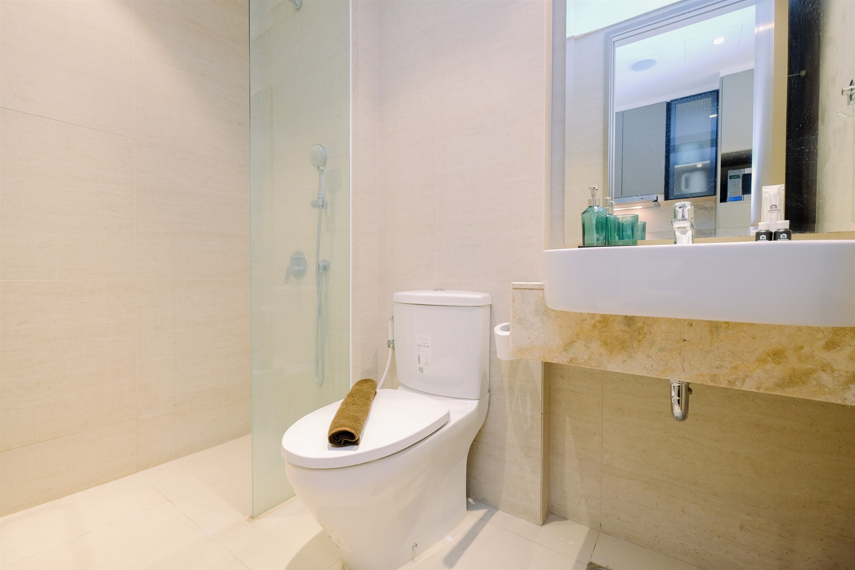 A modern bathroom with a toilet, a glass shower enclosure, and a sink with toiletries.